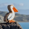 A chunky wooden white and orange pelican toy with a landscape background