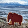 A chunky wooden brown toy mammoth with a landscape background