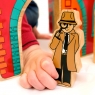 A child pushing a wooden toy detective character through a doorway
