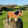 A chunky wooden brown shetland pony toy with a landscape background