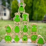 A stack of twelve wooden toy green characters showing emotions