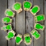 Twelve wooden toy green characters lay flat in a circle showing emotions