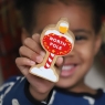 Child holding a red, white and gold North Pole sign toy