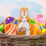 A chunky wooden toy white and pink Easter bunny in a basket with rainbow egg toys