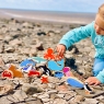 A stack of Lanka Kade wooden toy sea life animal figures on the beach including the shark