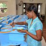 Sri Lankan artisan hand painting blue paint into the circular windows of the Noah's ark