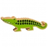 A wooden toy green crocodile in profile with a natural wood grain edge