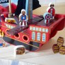 Close up of details on red wooden pirate ship, pirates and accessories on a wooden floor