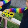 Chunky wooden yellow toy ambulance being played with by a toddler