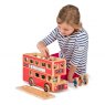 Child playing with red wooden double decker bus with roof removed and figurine characters in hand