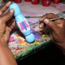 Sri Lankan artisan skilfully handpainting butterfly design onto a wooden skipping rope handle
