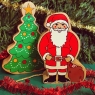 A chunky wooden Father Christmas toy figure standing next to Christmas tree