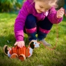 Child playing with a white, orange and black dog pull along toy in the garden