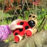 A child playing with a wooden red and black ladybird push along in the garden
