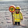 A chunky wooden yellow and black lollipop person toy figure at a crossing