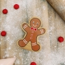 A chunky wooden gingerbread man toy figure in profile with a natural wood edge