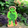 A chunky wooden green troll toy figure in profile